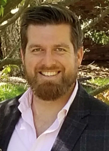 A man with a beard and mustache smiling for the camera.